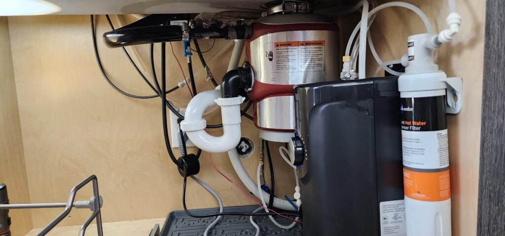 Reverse osmosis drain line and plumbing connections under kitchen sink