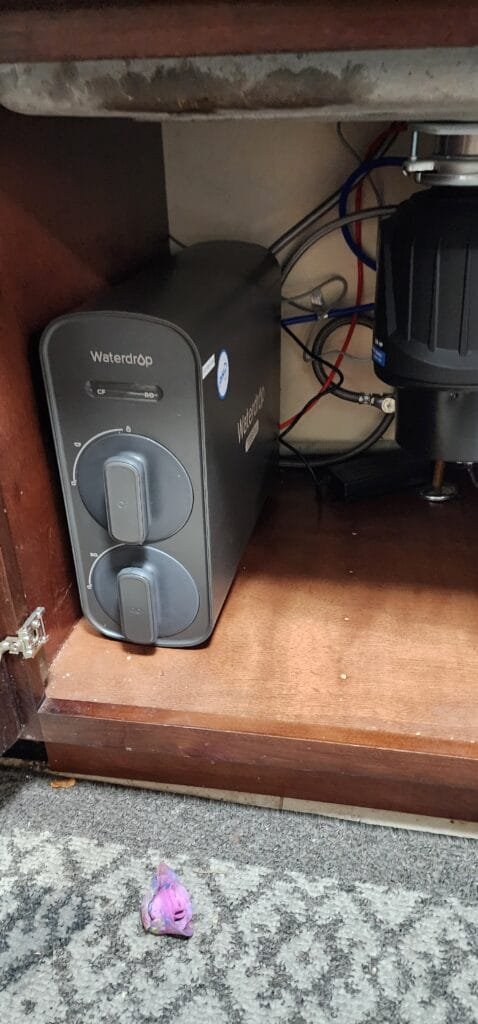 Under-sink water filtration unit installed inside kitchen cabinet